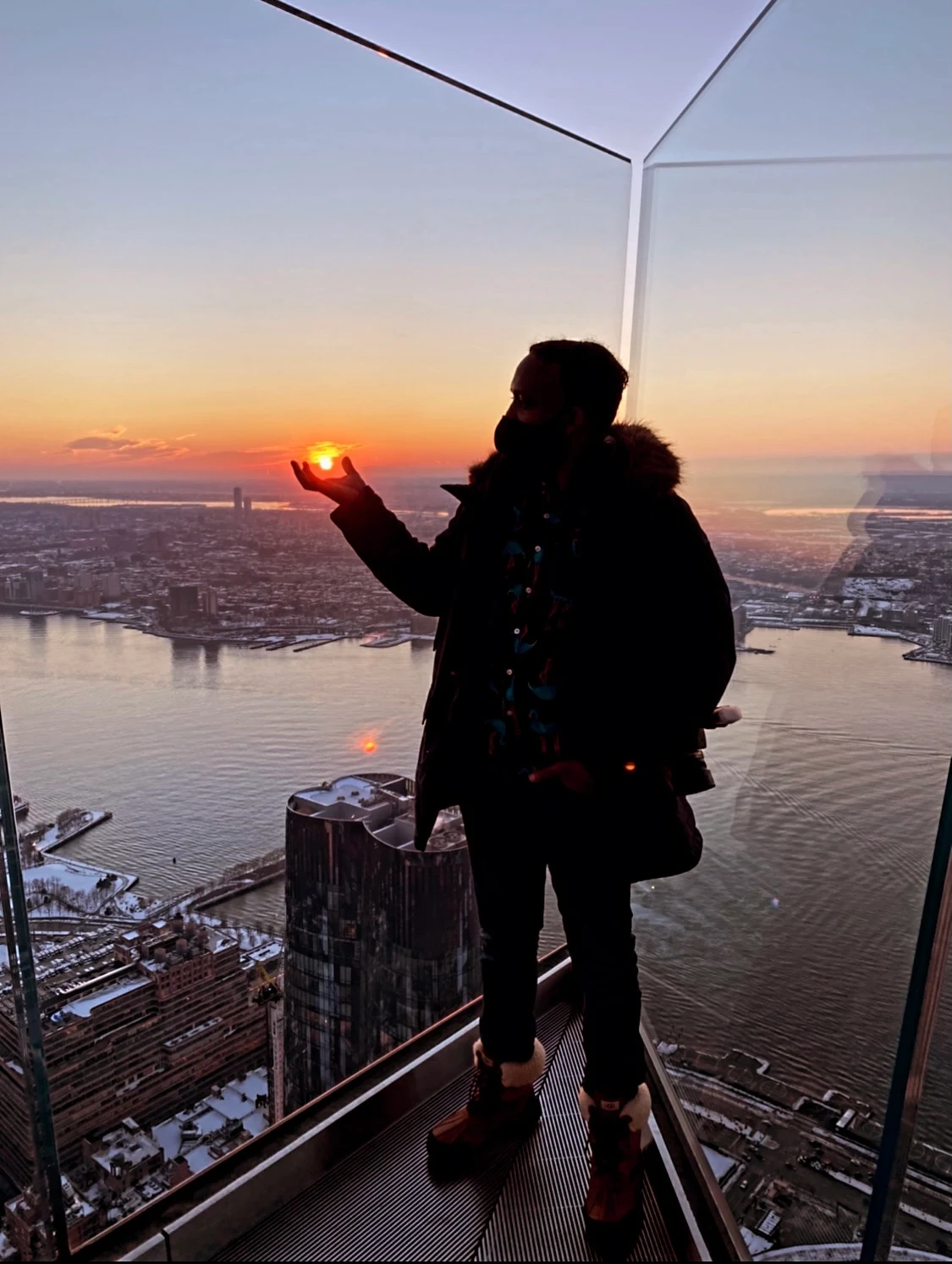 Dwight Robinson in silhouette, cupping the setting sun in his hand above the New York City skyline