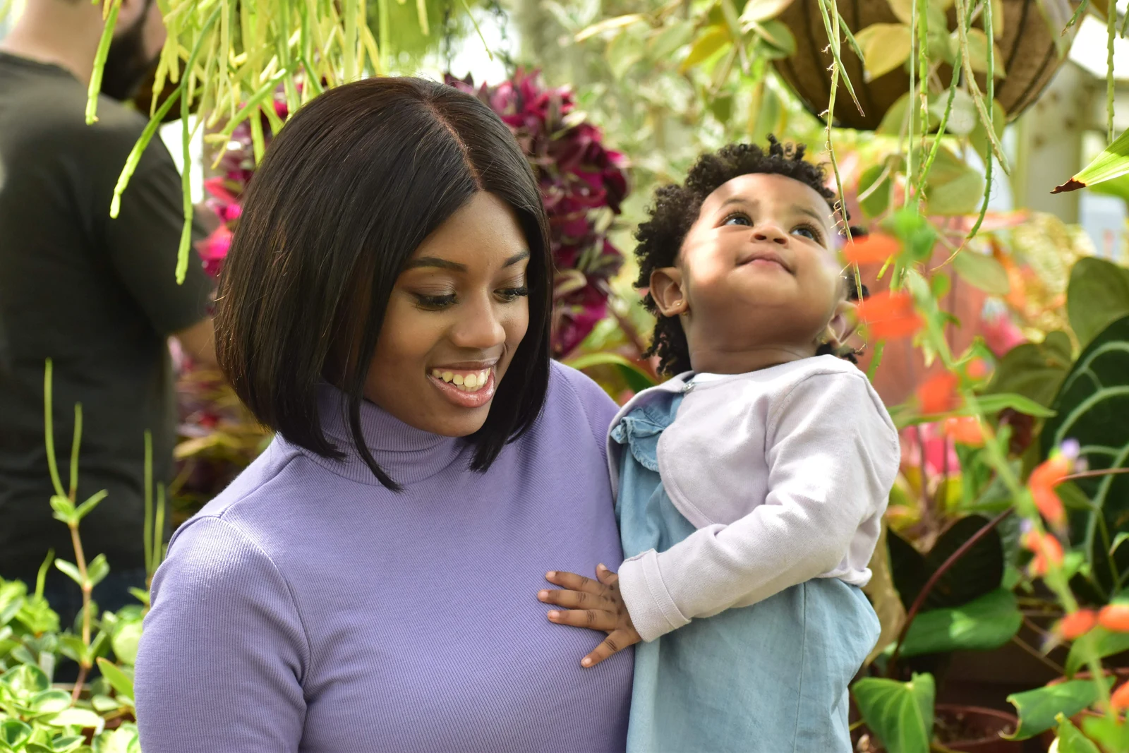 Mother and child sharing a moment among plants in a greenhouse