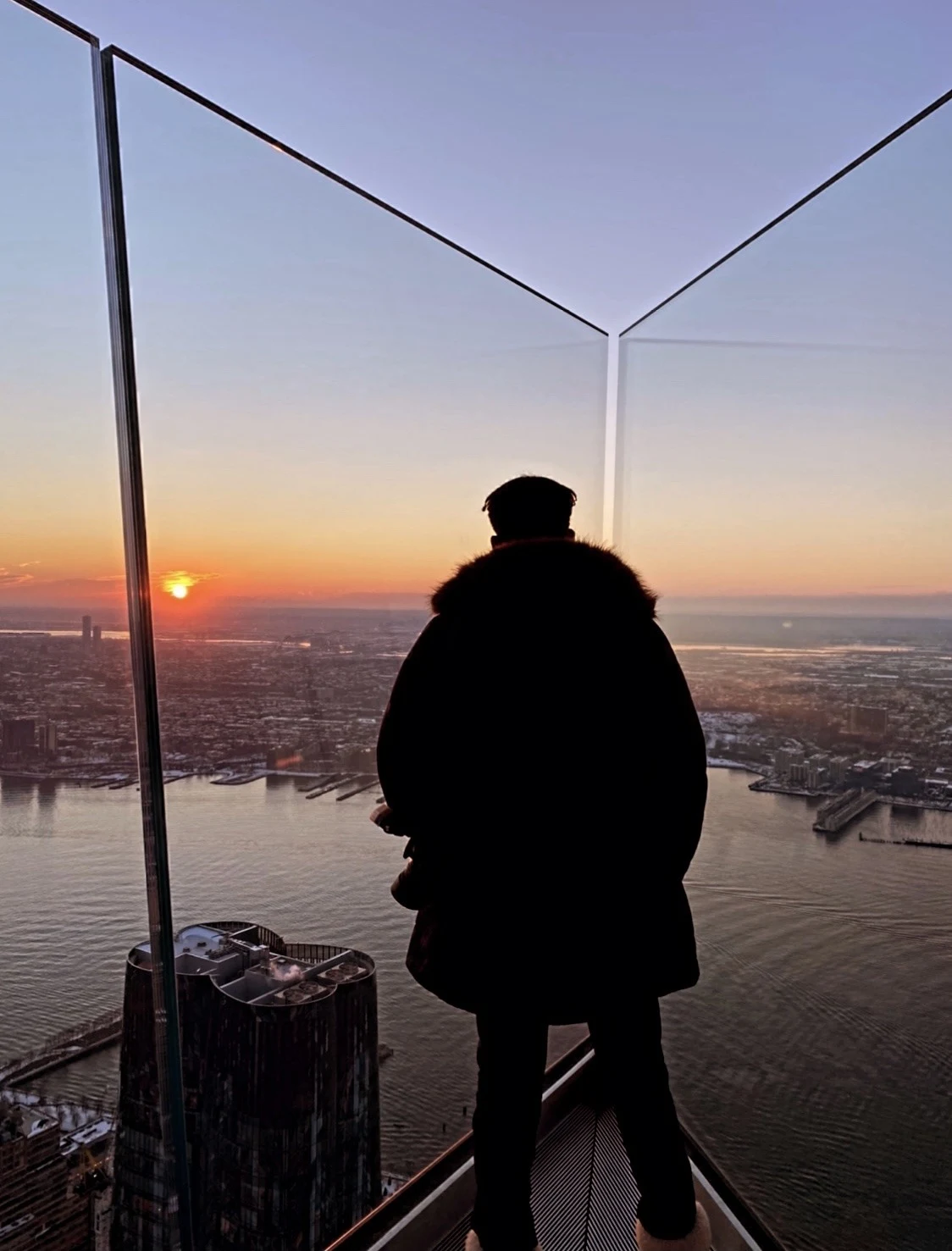 Silhouette of the photographer high above Manhattan at sunset, holding the sun in his hand