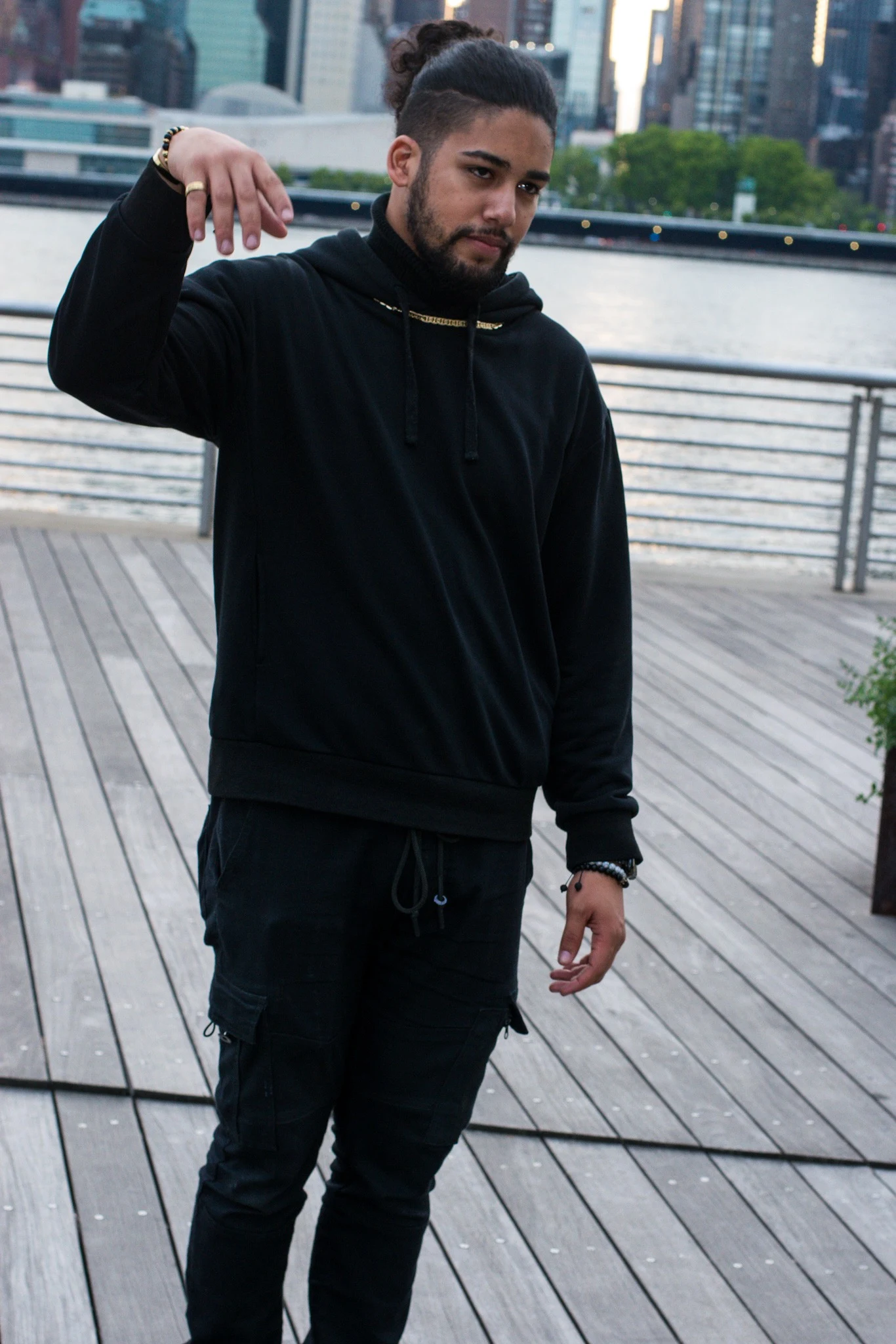 Young man in black posing on a waterfront deck