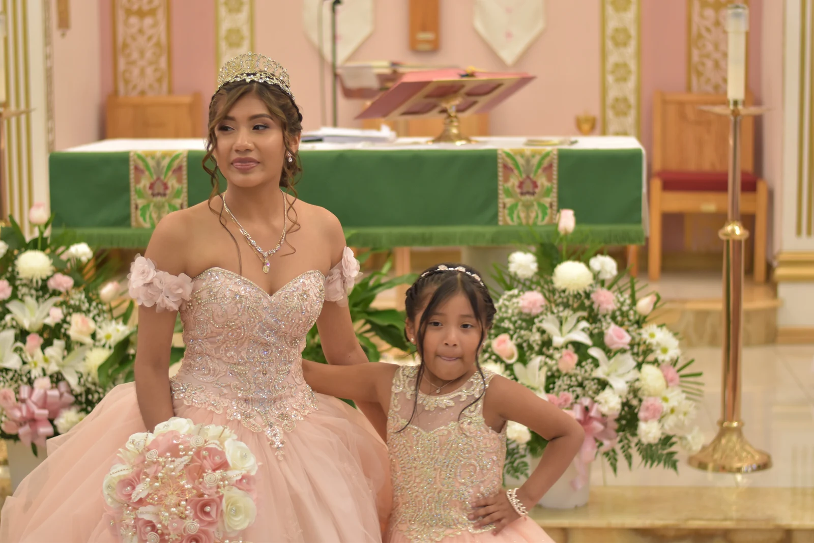 Quinceañera with a young girl in a matching dress at the church altar