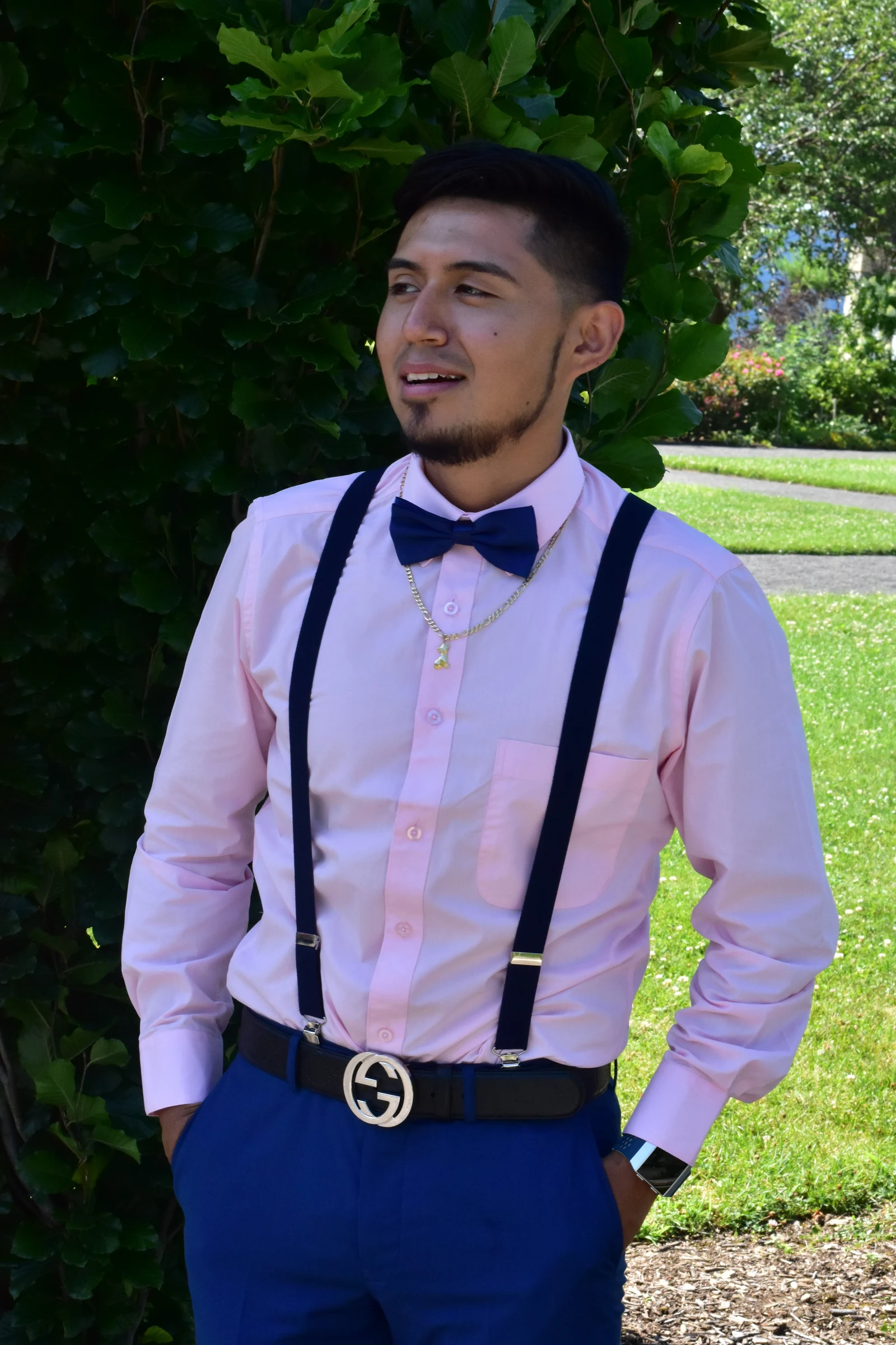 A chambelán in a pink shirt and bow tie smiling in the garden