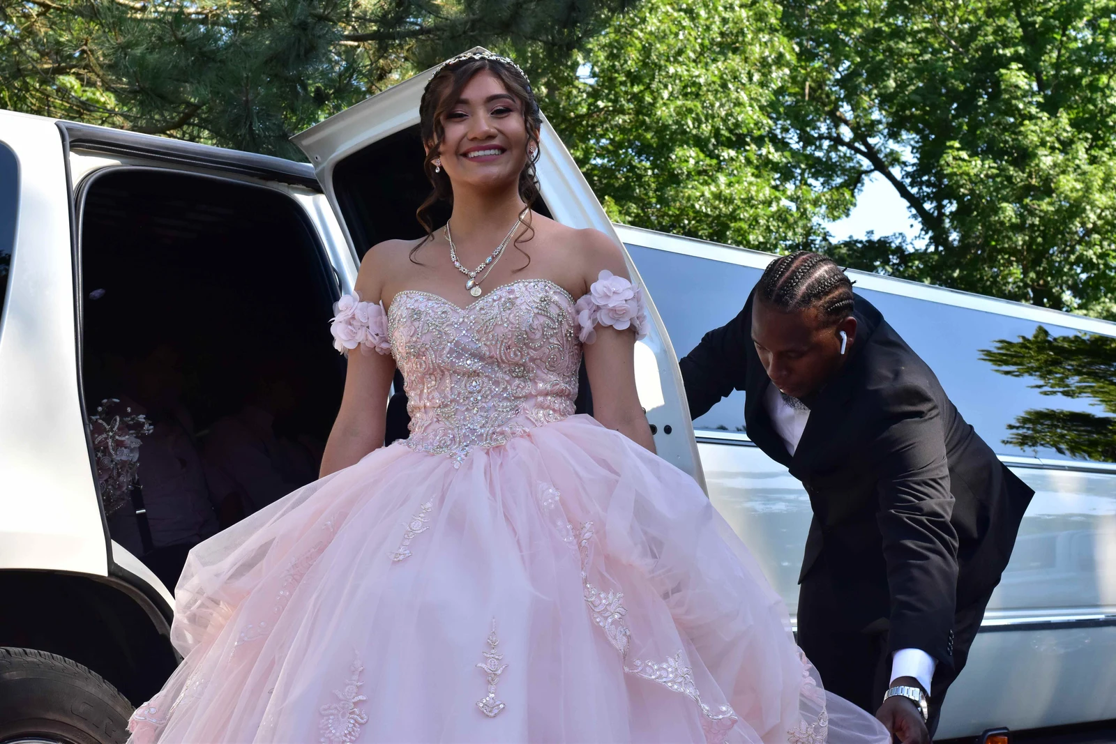Quinceañera stepping out of a limousine as the chauffeur helps her
