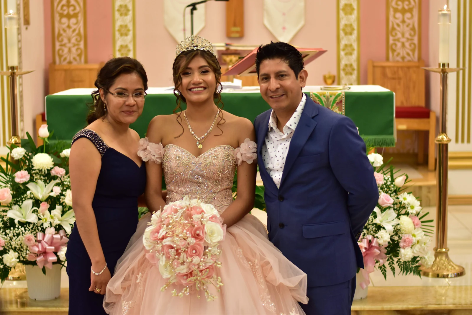 Quinceañera standing with her parents at the church altar