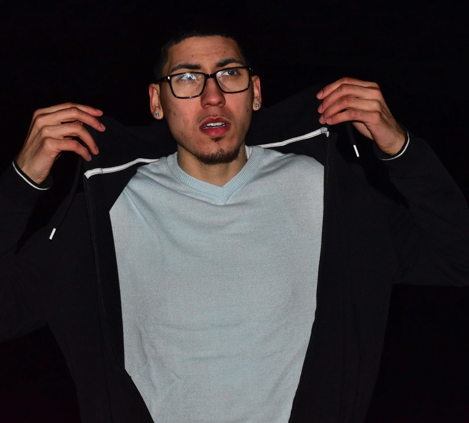 Night portrait of a young man opening his jacket under low light