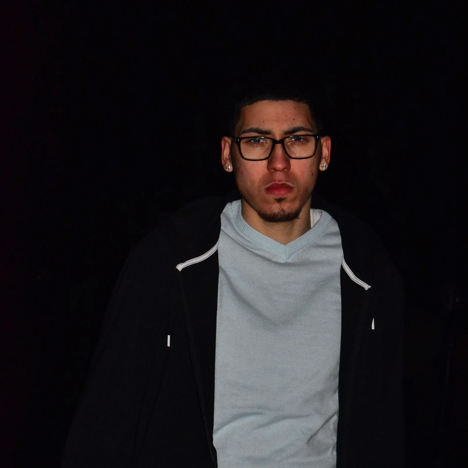Night portrait of a young man in a hooded jacket, calm and direct